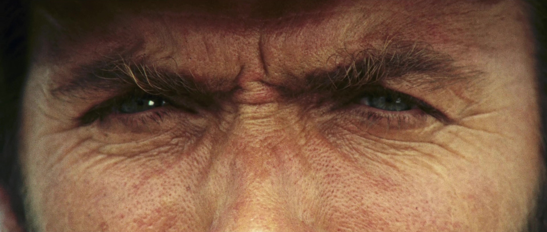 An extreme close-up of a man's eyes and furrowed brow
